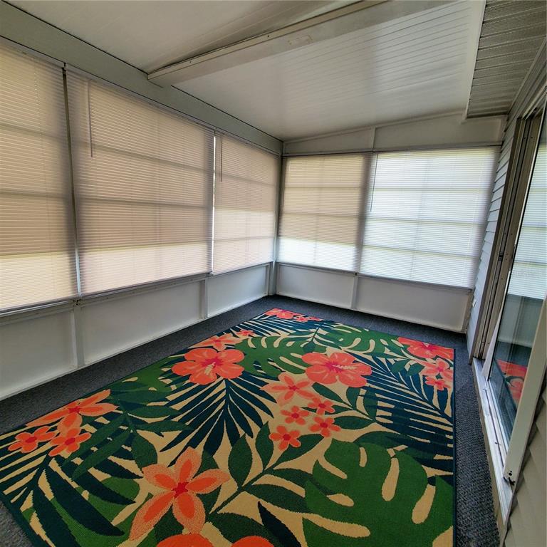 A room with dark wood-look flooring, light walls, and a sliding glass door with curtains — 6311 SW 106TH PLACE, OCALA, FL
