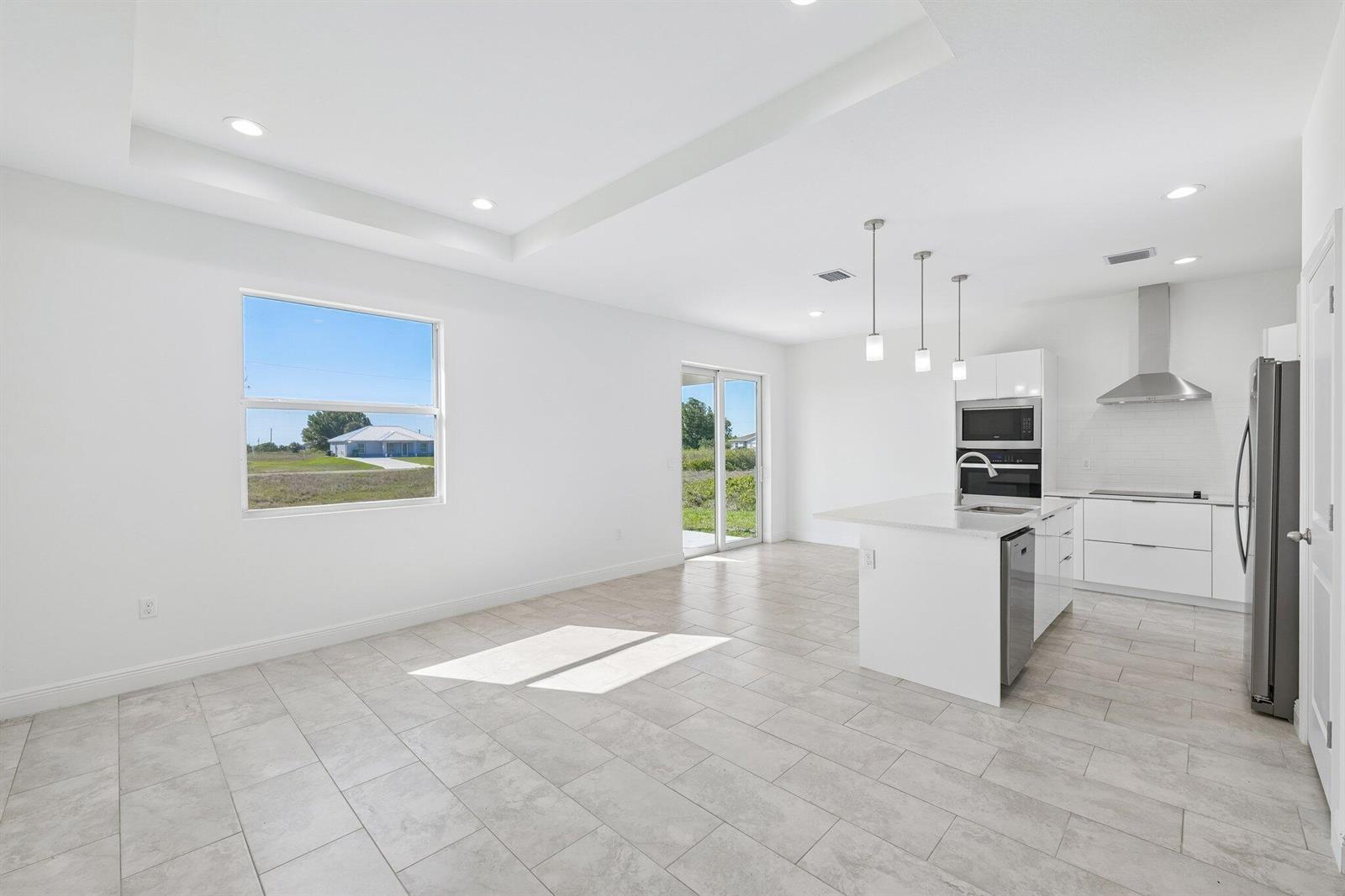 A bright, open-concept kitchen and dining area features white cabinetry, tile floors, and recessed lighting — 9006 S Castle Circle, FL 33935, FL