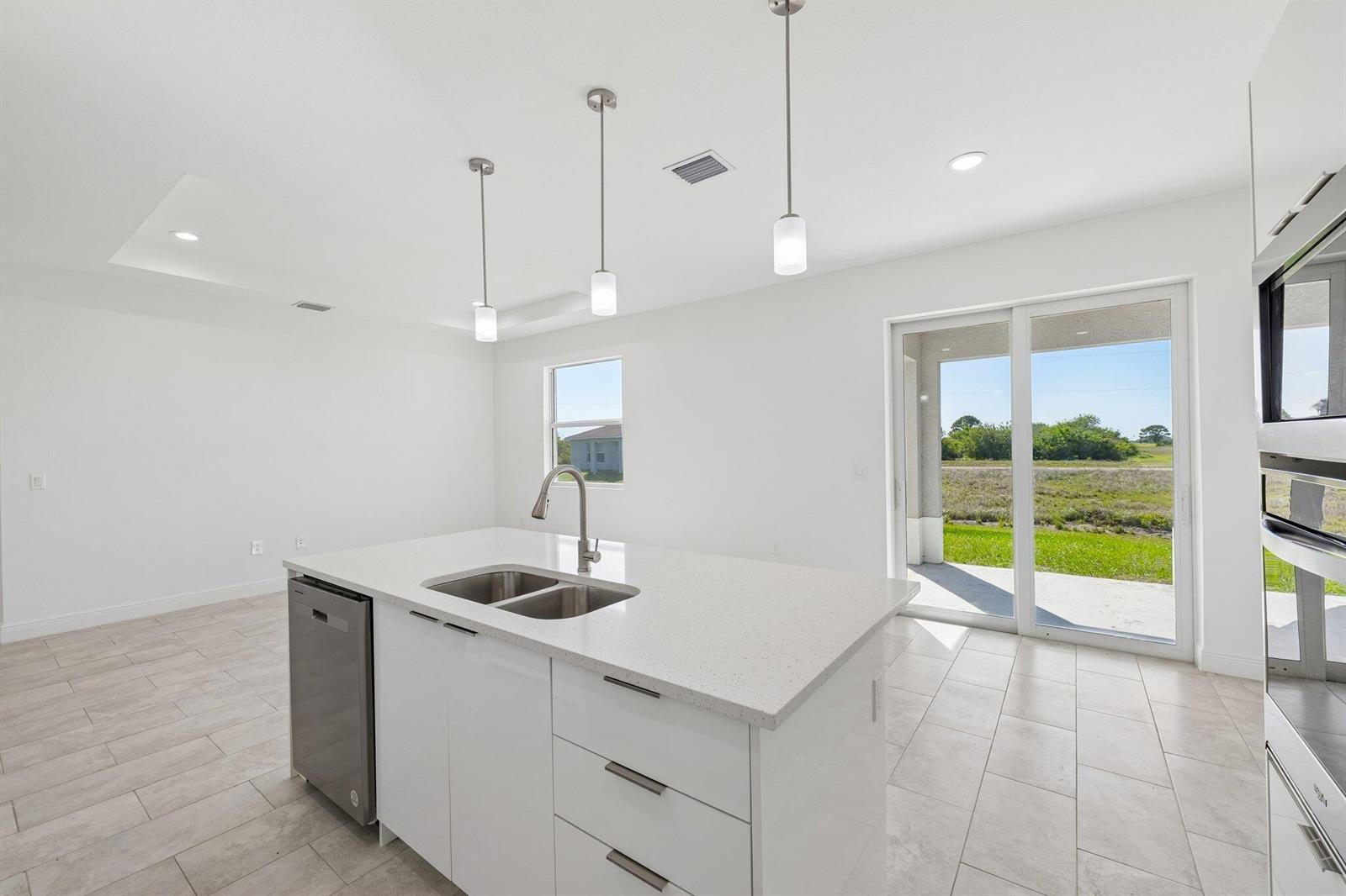 A modern kitchen island with a stainless steel sink sits before a sliding glass door — 9006 S Castle Circle, FL 33935, FL