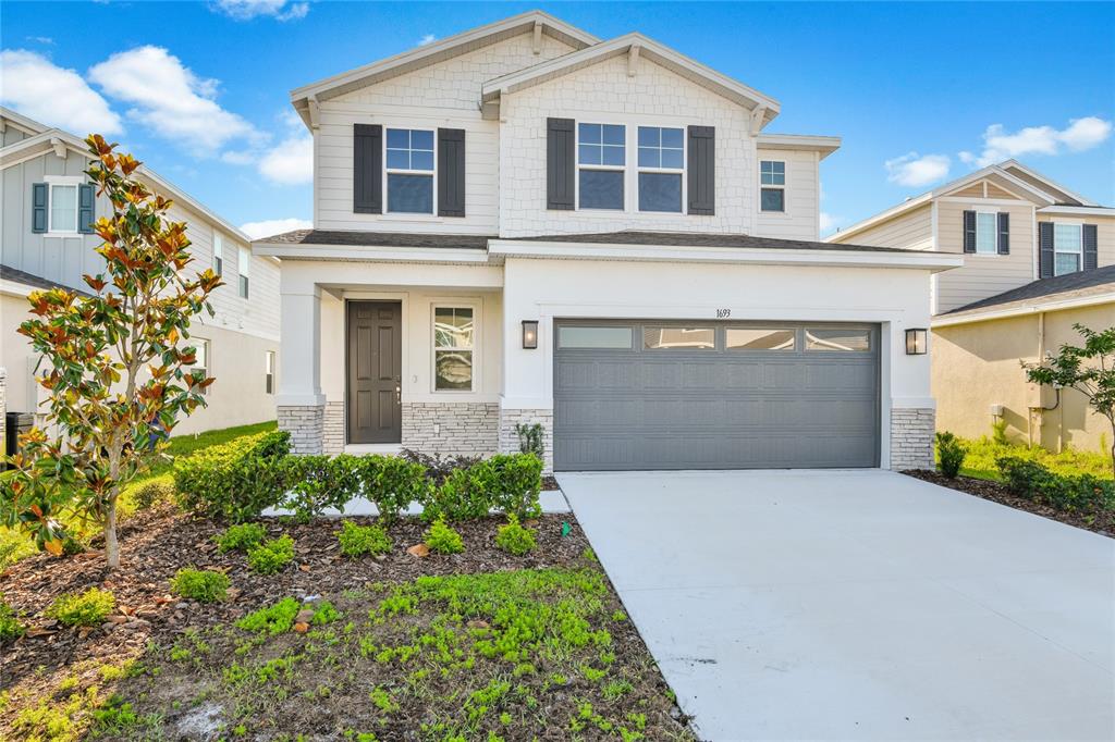 A two-story suburban house with a gray garage door, white siding, and a concrete driveway — 1693 CROOKED CREEK STREET, ST CLOUD, FL