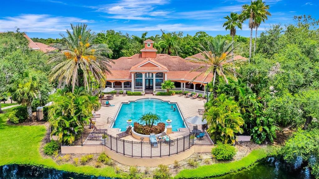 An aerial view of a community clubhouse featuring a swimming pool, patio, and palm trees — 4106 CENTRAL SARASOTA PARKWAY UNIT 1026, SARASOTA, FL