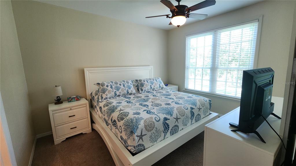 A bedroom features a white bed frame, a patterned quilt, a nightstand, and a television — 4106 CENTRAL SARASOTA PARKWAY UNIT 1026, SARASOTA, FL