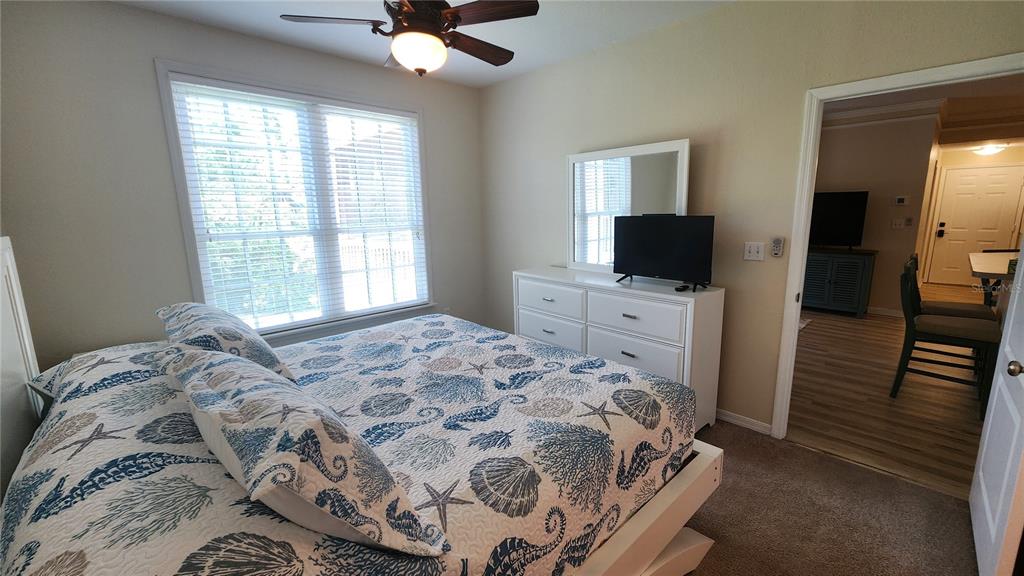 A bedroom features a bed with a seashell-patterned quilt, a white dresser, and a ceiling fan — 4106 CENTRAL SARASOTA PARKWAY UNIT 1026, SARASOTA, FL