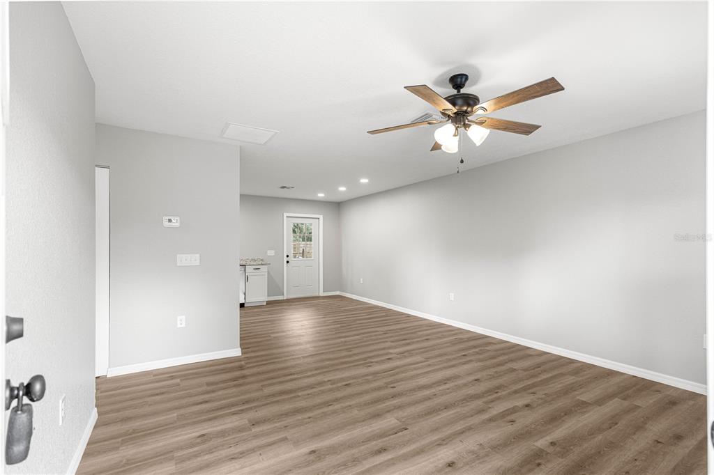 An empty room with light gray walls, wood-look flooring, a ceiling fan, and a back door — 11060 NE 145TH LANE, FORT MC COY, FL