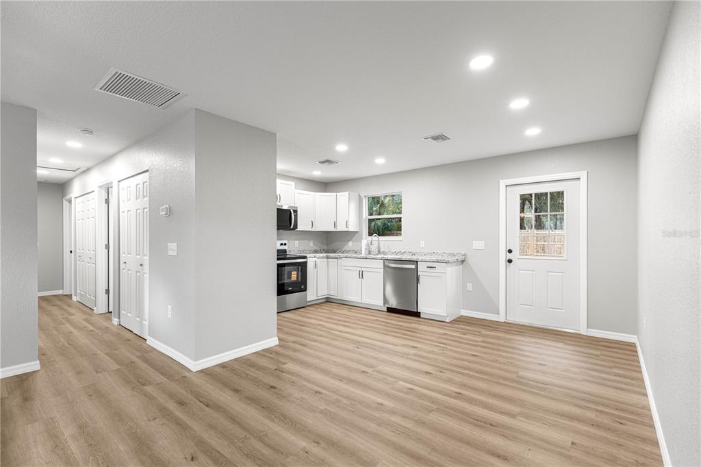 A kitchen with white cabinets, stainless steel appliances, and light wood-look flooring — 11060 NE 145TH LANE, FORT MC COY, FL