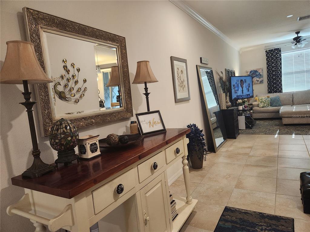 A hallway with a wooden console table, mirror, and lamps leads into a living room — 3901 SILVERLAKE WAY, WESLEY CHAPEL, FL