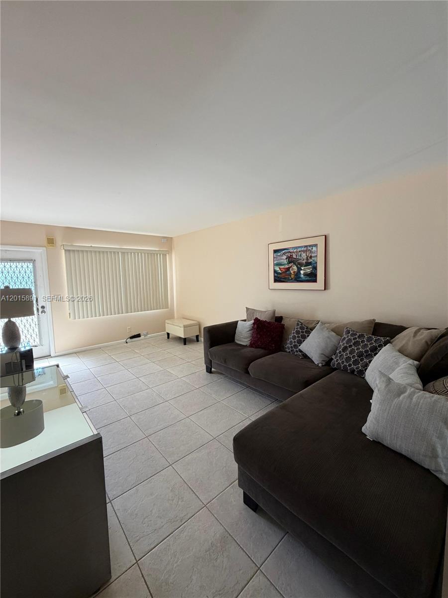 A living room features a large brown sectional sofa, tile flooring, and a sliding glass door — 3032 Hythe B # 3032, Boca Raton FL 33434, BOCA RATON, FL