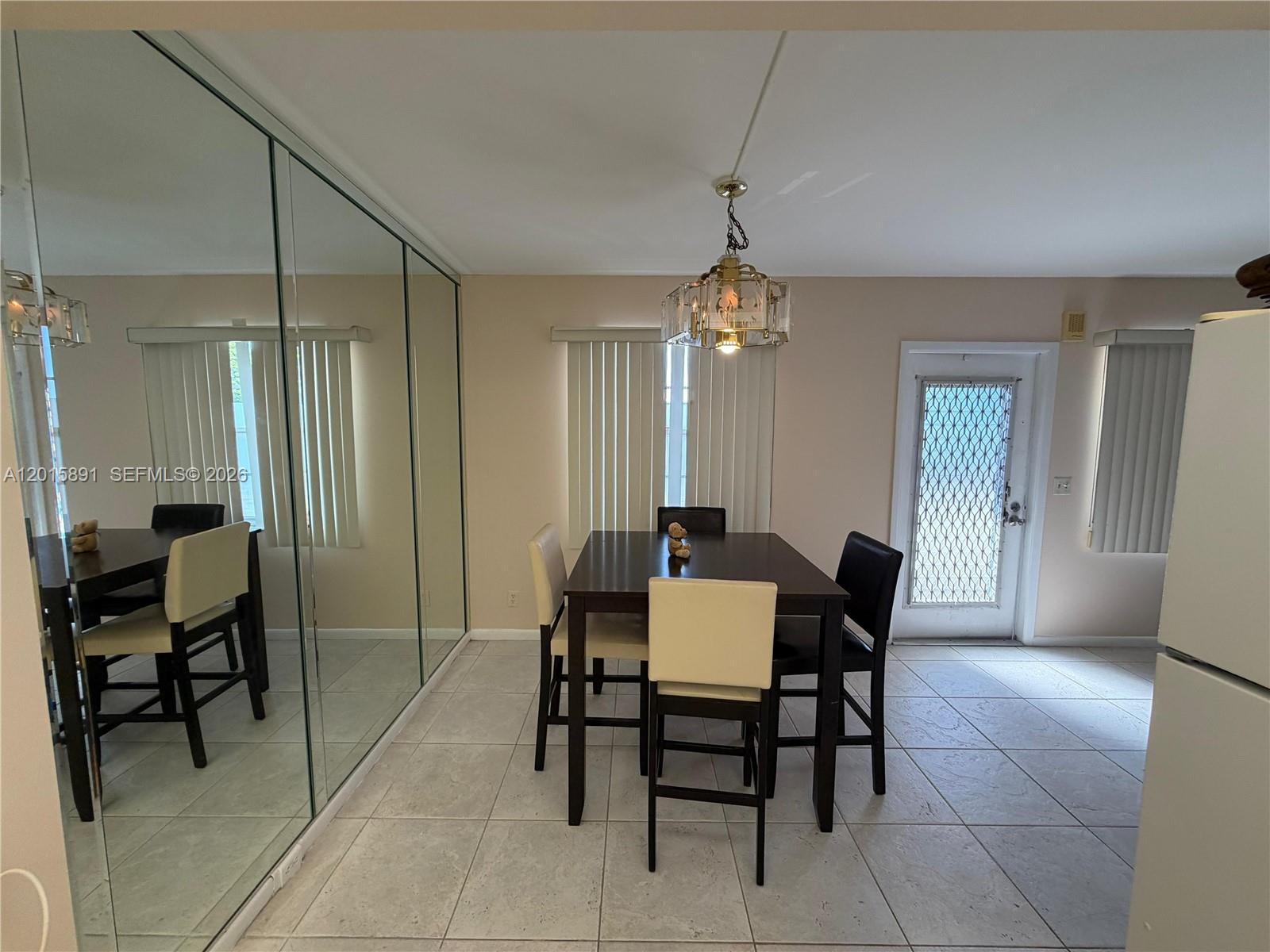 A dining area features a dark wood table, four chairs, a chandelier, and mirrored walls — 3032 Hythe B # 3032, Boca Raton FL 33434, BOCA RATON, FL