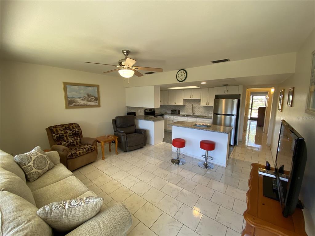 An open-concept living room and kitchen featuring tile flooring, a breakfast bar, and stainless appliances — 711 SPRINGER DRIVE UNIT 9, LAKE WALES, FL