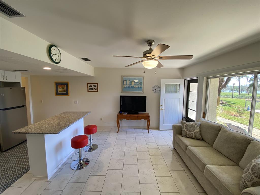 A living room with a kitchen island, red bar stools, tile floors, and a sofa — 711 SPRINGER DRIVE UNIT 9, LAKE WALES, FL