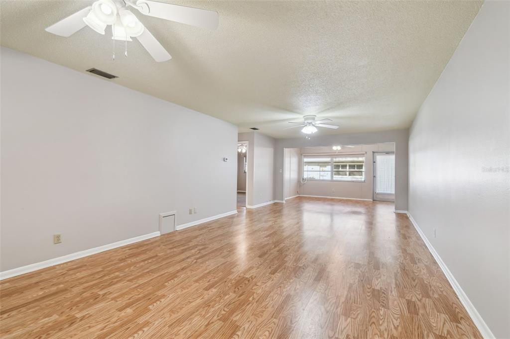 An empty living room with light-colored walls, wood-look flooring, and two ceiling fans — 11200 102ND AVENUE UNIT 33, SEMINOLE, FL