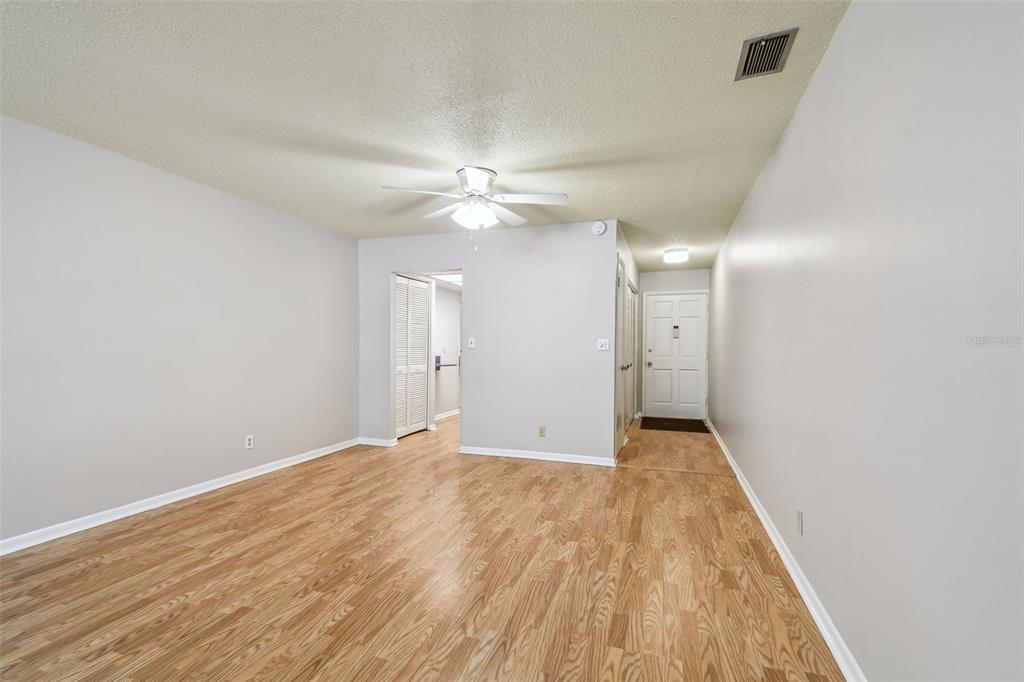 An empty room with light wood-look flooring, white walls, a ceiling fan, and an entryway — 11200 102ND AVENUE UNIT 33, SEMINOLE, FL