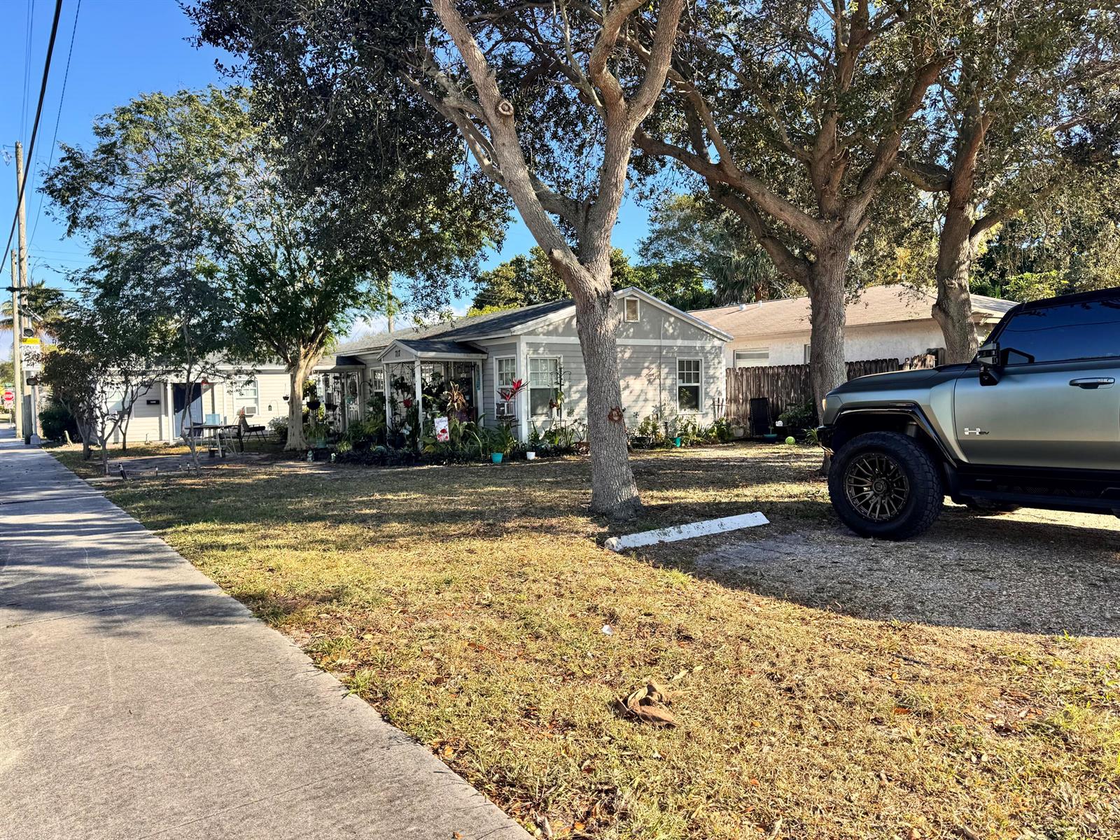A single-story house with a front porch sits behind a lawn with large trees — 717 8th Avenue N, FL 33460, FL