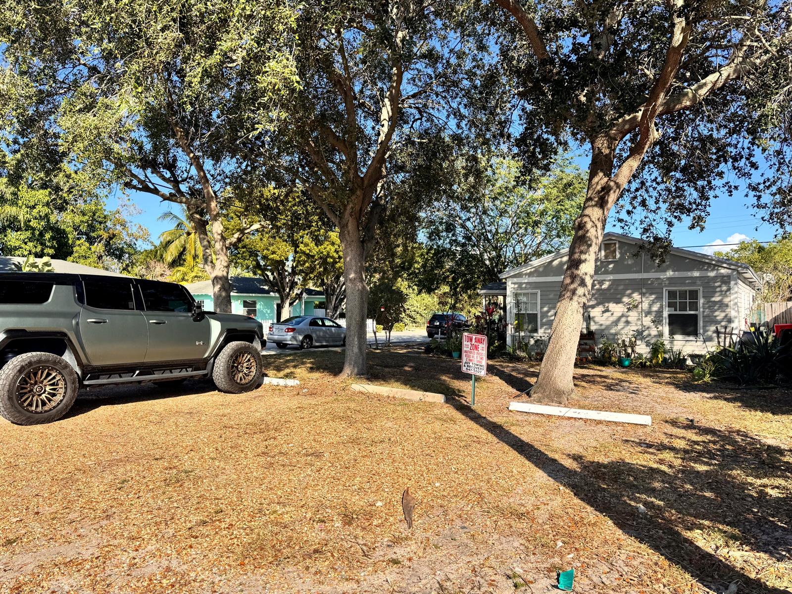 A large gray SUV is parked on a dirt lot in front of a house — 717 8th Avenue N, FL 33460, FL