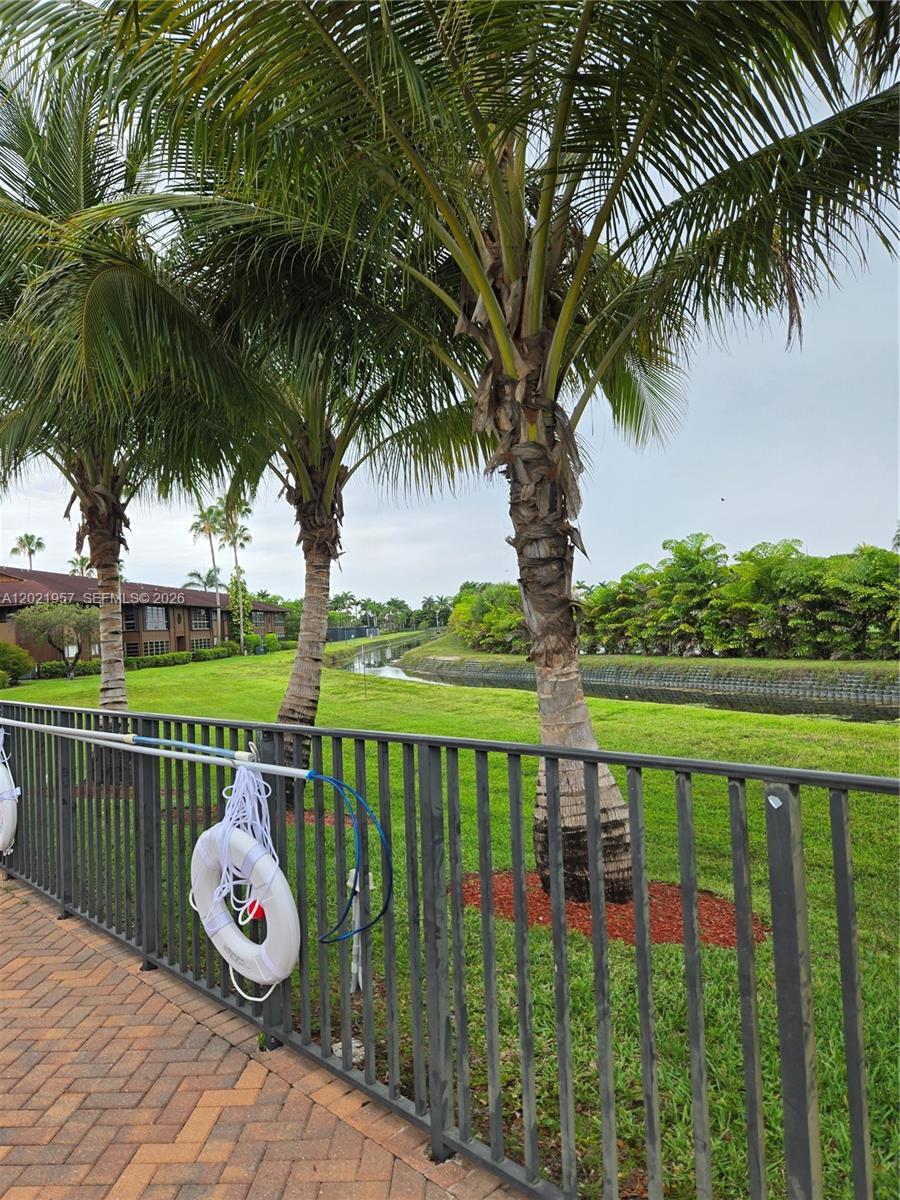 A view of a canal and palm trees from a brick-paved pool deck — 4760 NW 102nd Ave # 12, Doral FL 33178, DORAL, FL