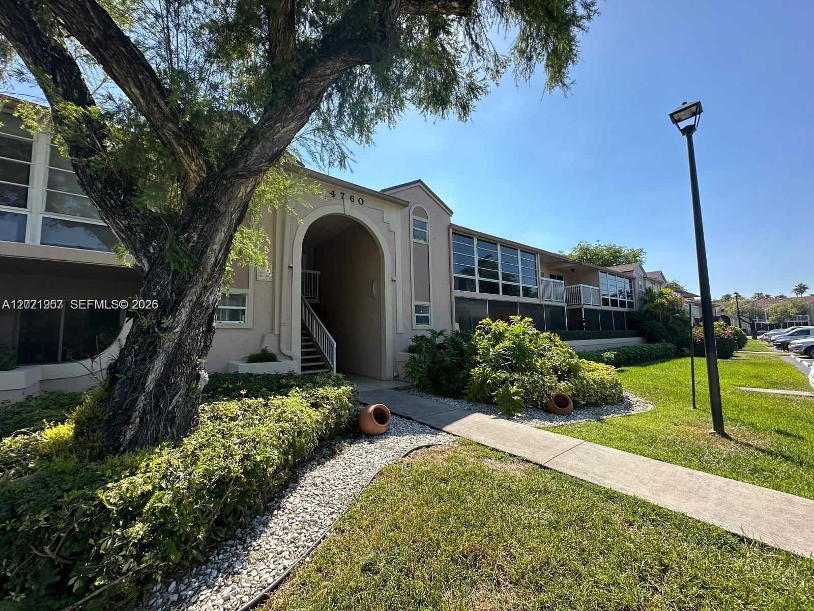 A two-story apartment building exterior features a large arched entryway, landscaping, and a sidewalk — 4760 NW 102nd Ave # 12, Doral FL 33178, DORAL, FL