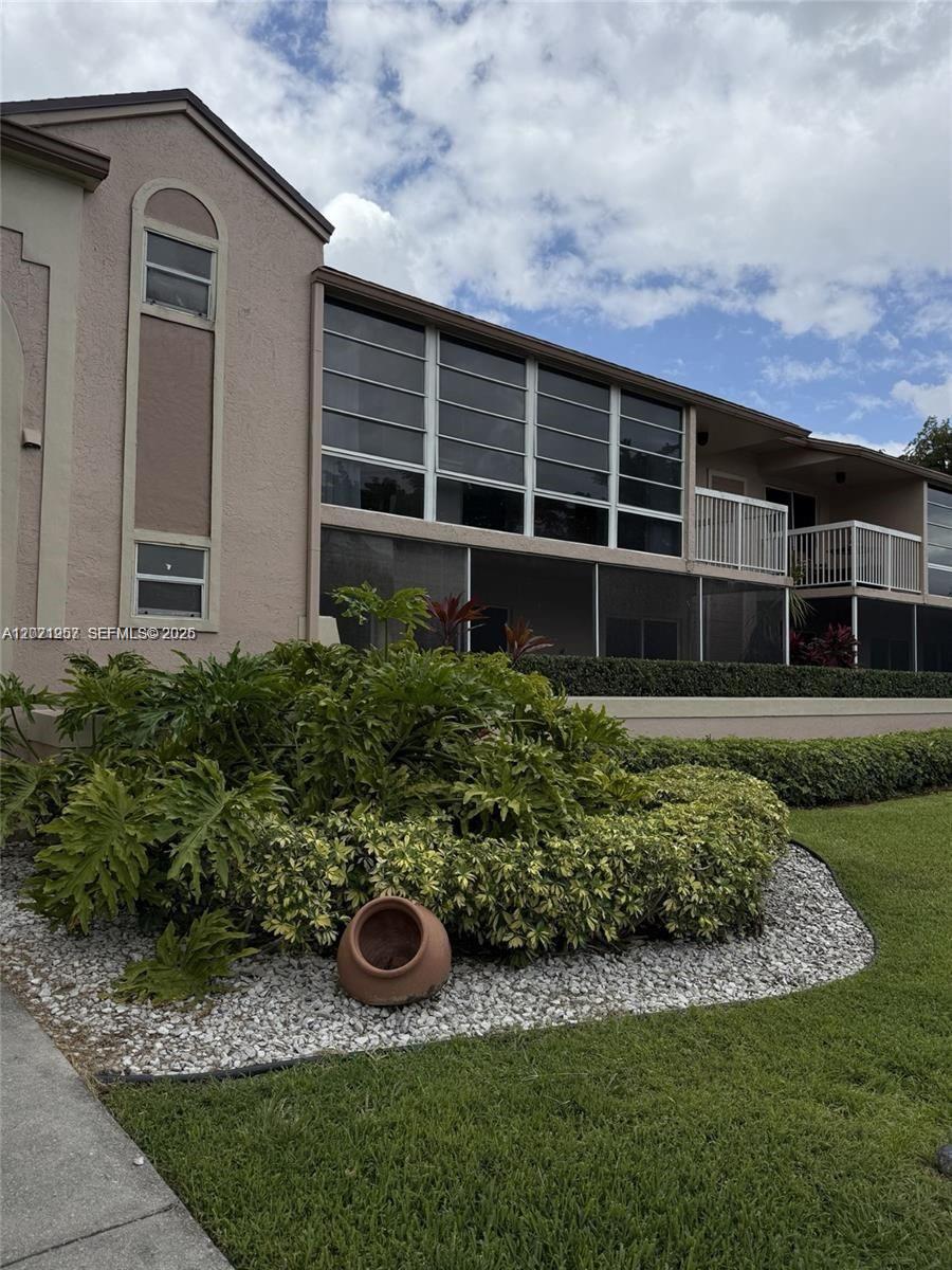 A two-story building features a screened-in patio, balconies, and a landscaped garden bed — 4760 NW 102nd Ave # 12, Doral FL 33178, DORAL, FL