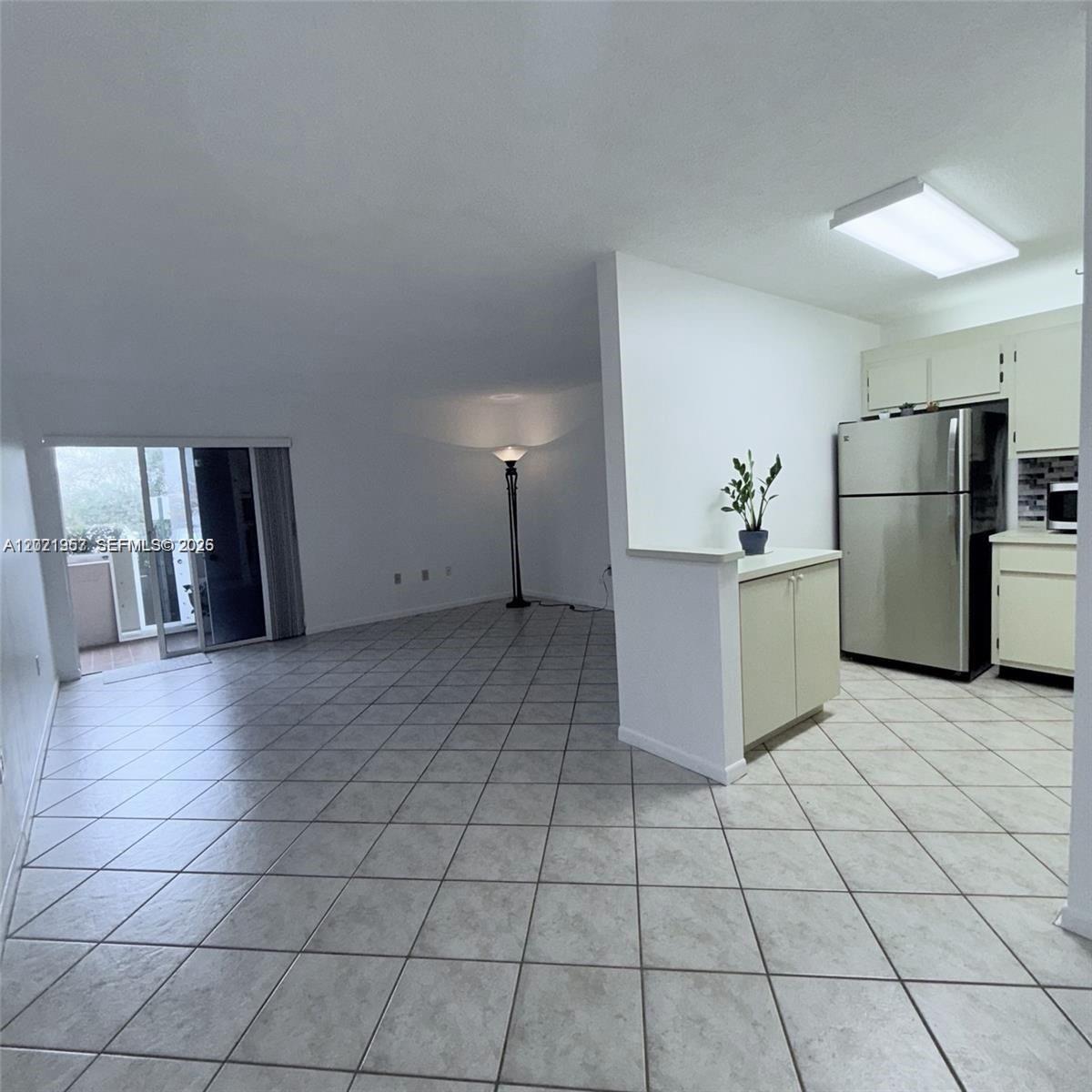 A kitchen with stainless steel appliances opens into a living area with tiled floors — 4760 NW 102nd Ave # 12, Doral FL 33178, DORAL, FL