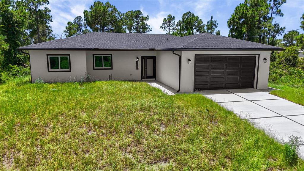 A single-story house with a white stucco exterior, dark trim, and a two-car garage — 1142 DUTCHESS STREET E, LEHIGH ACRES, FL