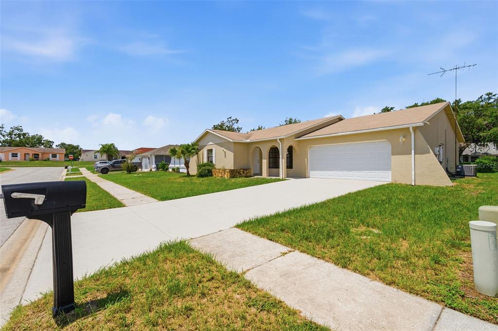 A single-story house with a tan exterior, a two-car garage, and a concrete driveway — 18813 GREEN PARK ROAD, HUDSON, FL