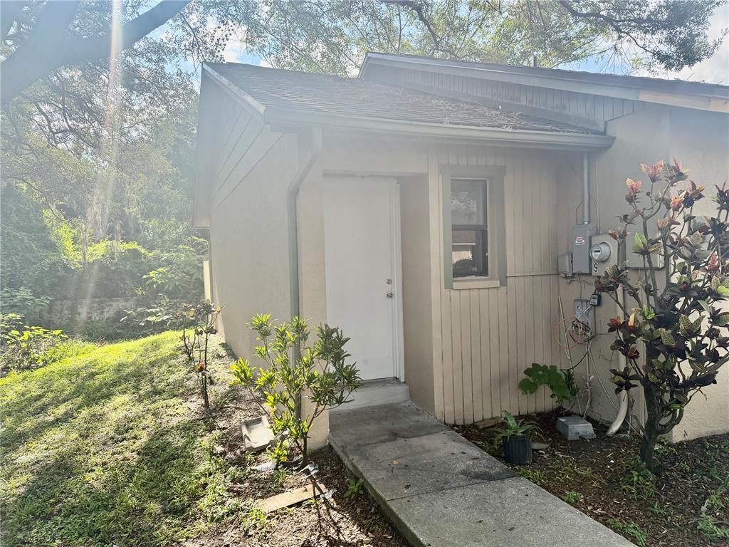 A concrete walkway leads to the white front door of a tan, single-story residential building — 918 OTTO VILLA PLACE UNIT 9, TAMPA, FL