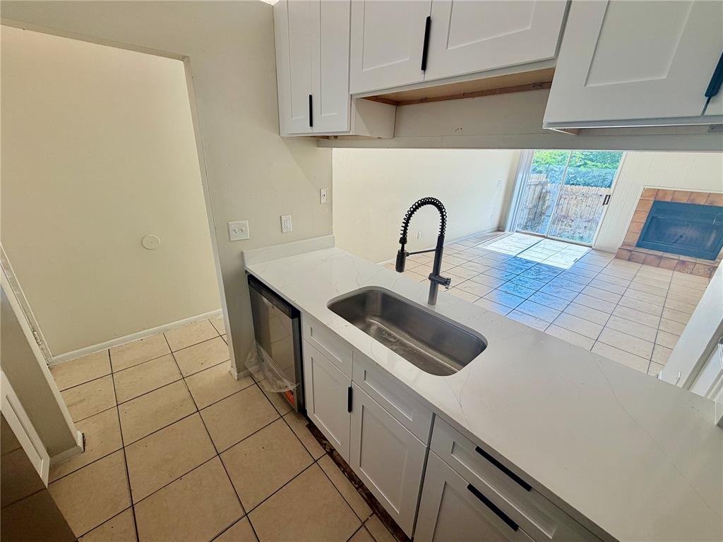A kitchen with white cabinets, a stainless steel sink, and a view into the living area — 918 OTTO VILLA PLACE UNIT 9, TAMPA, FL