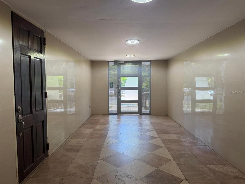 A tiled entryway features a dark wooden door and a glass-paneled exterior door — 1 CLL ALMONTE UNIT 1707, SAN JUAN, PR