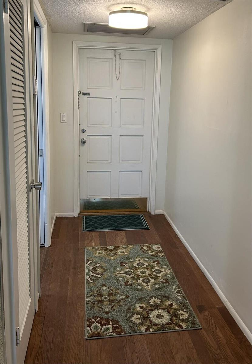 An entryway features wood flooring, a white paneled door, and a patterned area rug — 2651 S Course Drive # 509, Pompano Beach FL 33069, POMPANO BEACH, FL