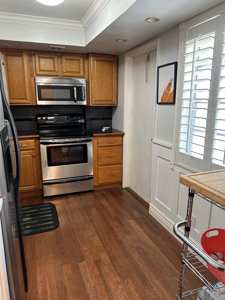A kitchen with wood cabinets, stainless steel appliances, dark countertops, and hardwood flooring — 2651 S Course Drive # 509, Pompano Beach FL 33069, POMPANO BEACH, FL