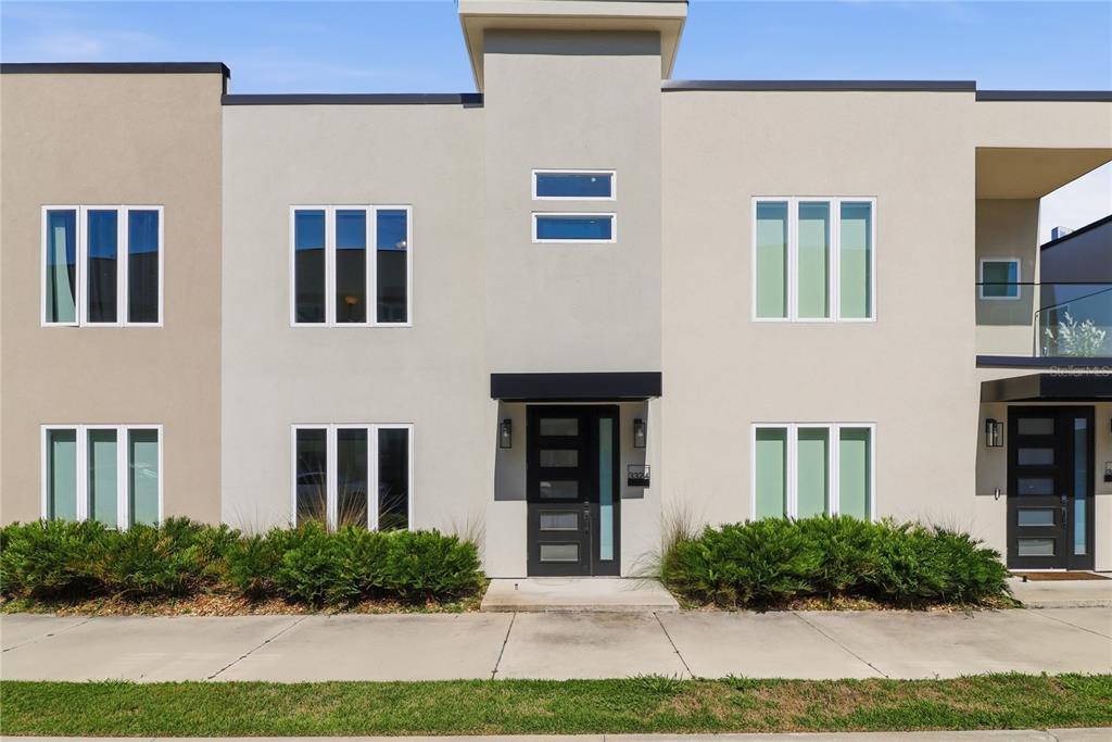 A modern two-story townhouse exterior with light-colored stucco, dark-framed windows, and a front entrance — 3324 SW 49TH TERRACE, GAINESVILLE, FL