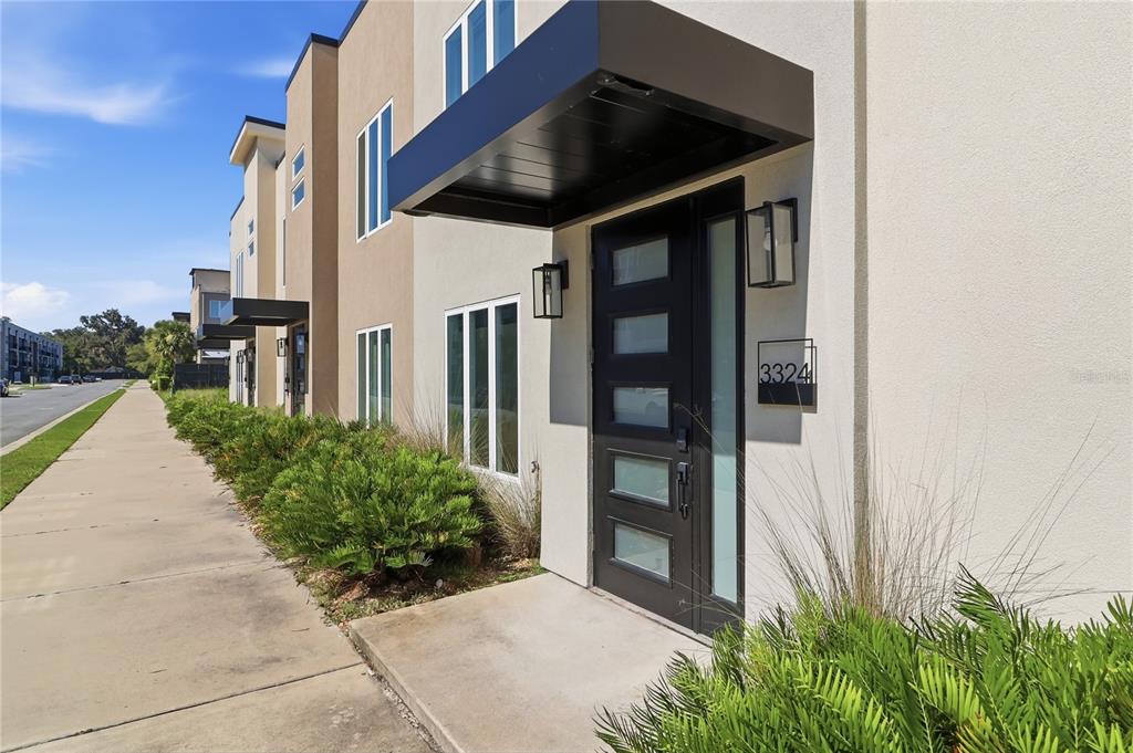 The exterior of a modern townhouse features a black front door and metal awning — 3324 SW 49TH TERRACE, GAINESVILLE, FL