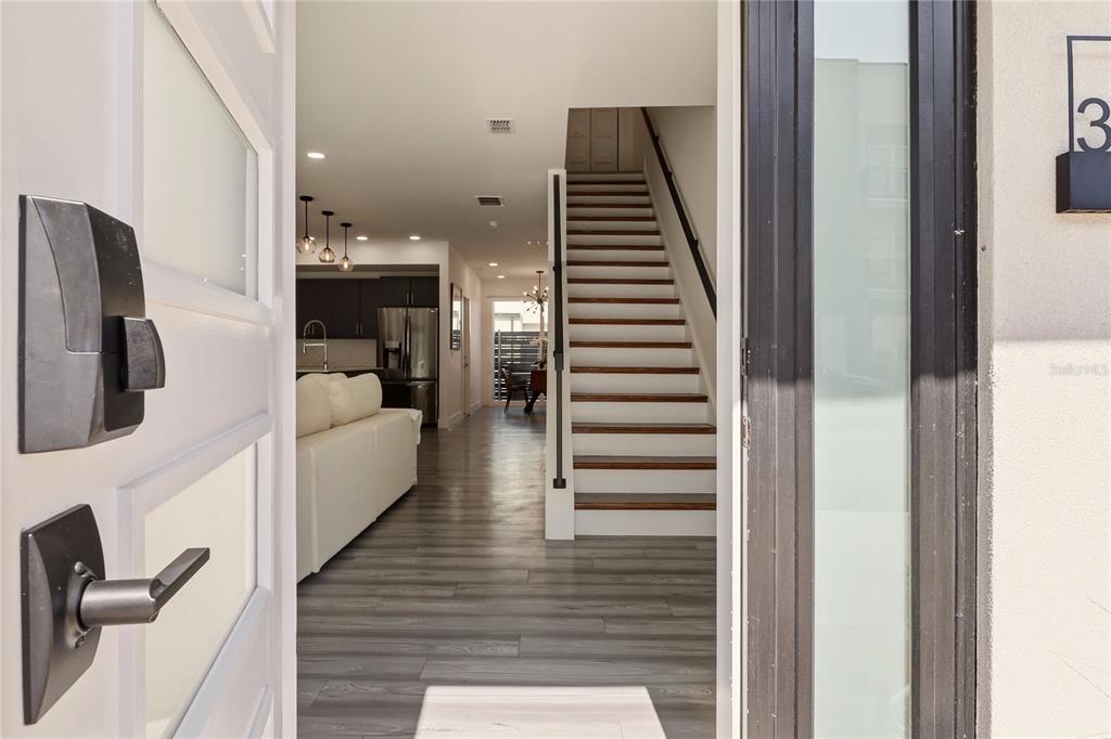 A view through an open front door reveals a staircase, living area, and modern kitchen — 3324 SW 49TH TERRACE, GAINESVILLE, FL