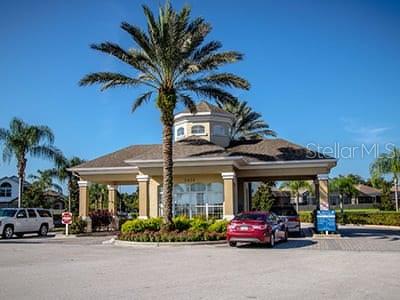 A palm tree stands in front of a community clubhouse with a covered entrance — 2307 BUTTERFLY PALM WAY UNIT # 102, KISSIMMEE, FL