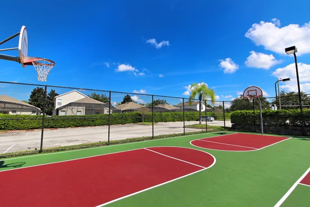 An outdoor basketball court with two hoops and a chain-link fence under a blue sky — 2307 BUTTERFLY PALM WAY UNIT # 102, KISSIMMEE, FL
