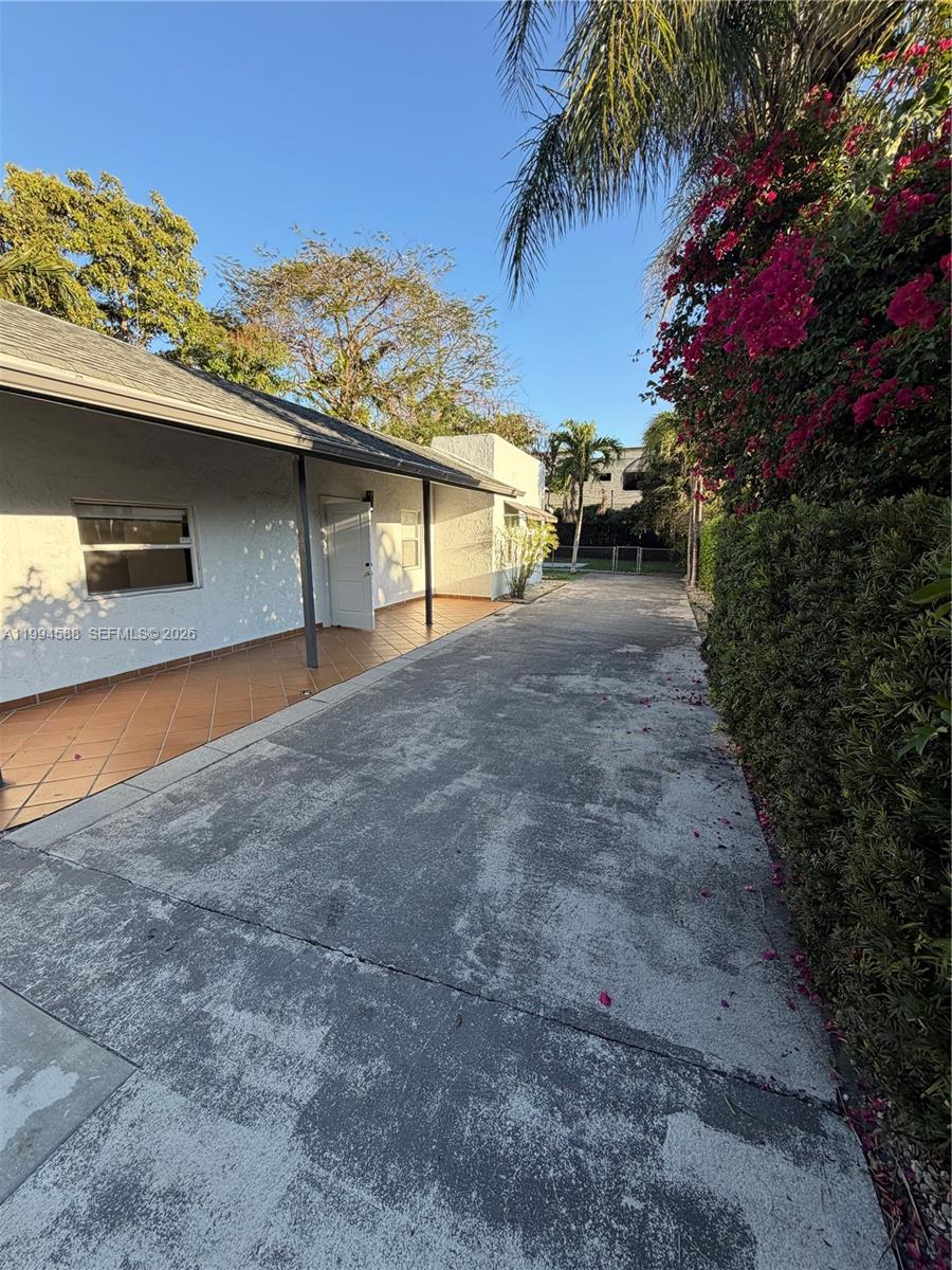 A concrete driveway runs alongside a house with a tiled patio and a hedge — 3373 SW 29th Ter, Miami FL 33133, MIAMI, FL