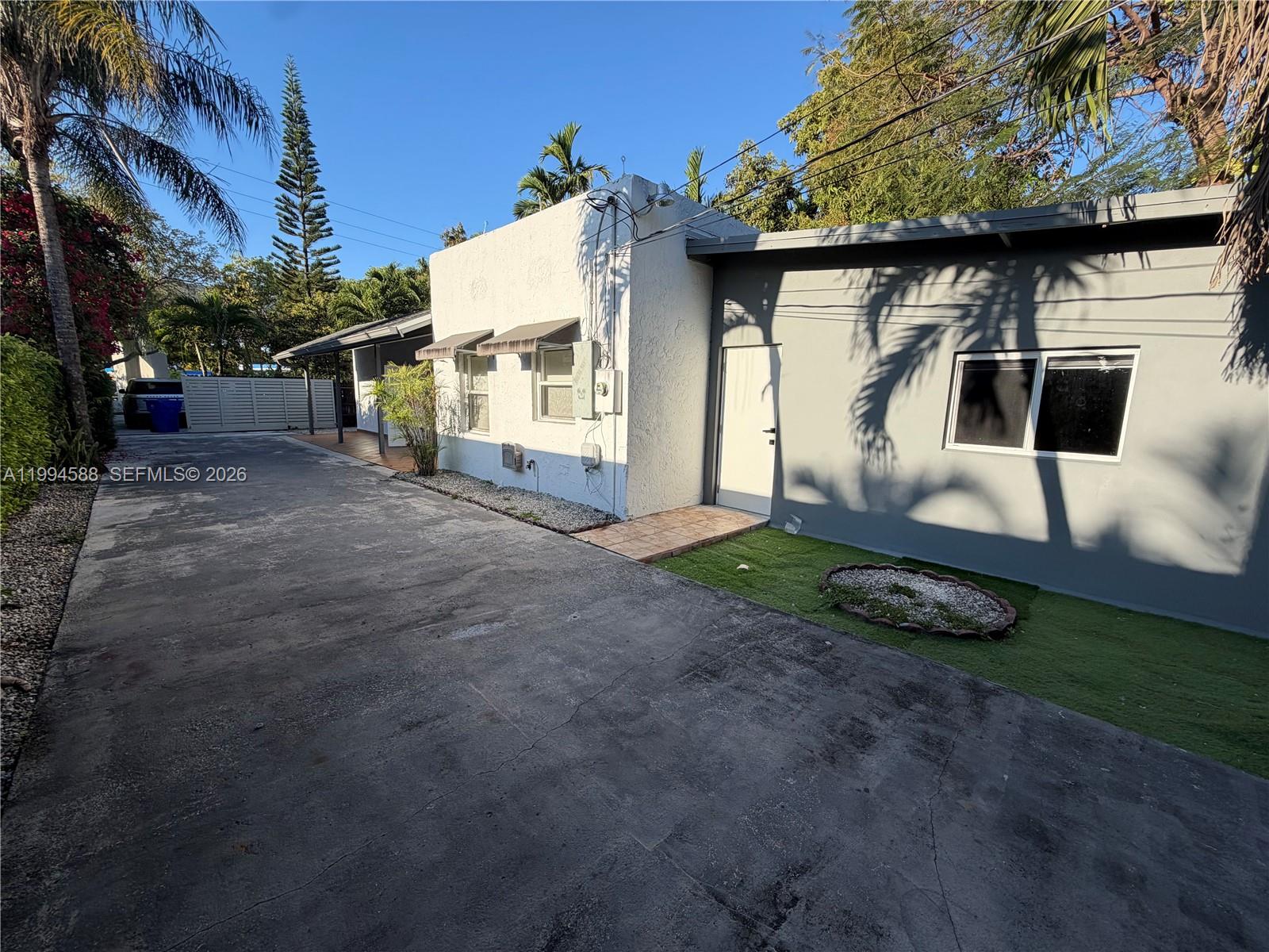 A concrete driveway leads to a white stucco building and an adjacent gray structure — 3373 SW 29th Ter, Miami FL 33133, MIAMI, FL