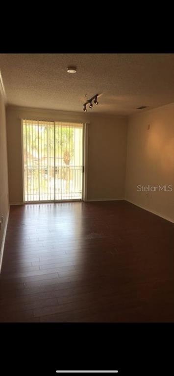 An empty room with dark wood-look flooring and a sliding glass door leading to a balcony — 18001 RICHMOND PLACE DRIVE UNIT 220, TAMPA, FL