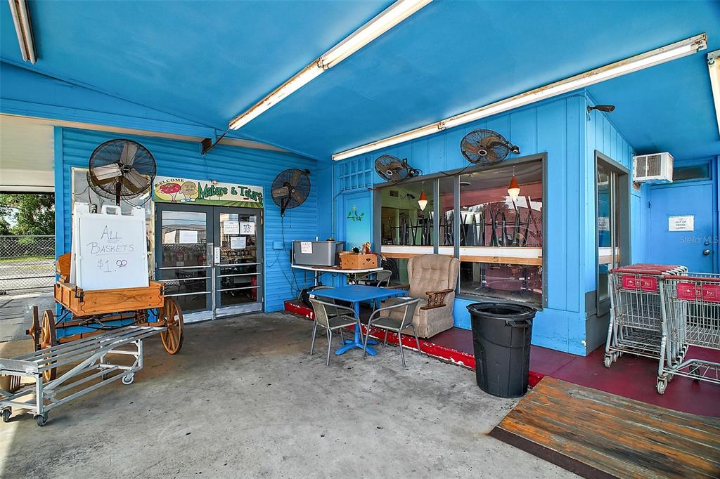 The exterior of a blue building features a covered patio with seating and shopping carts — 454 N PARK AVENUE, APOPKA, FL