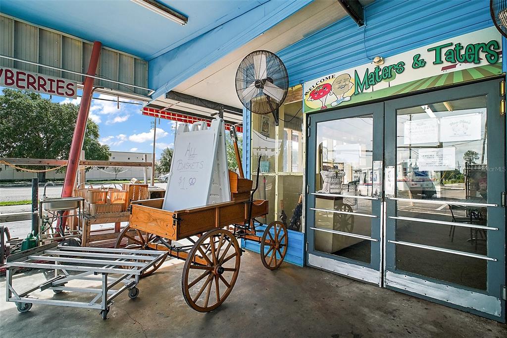 An outdoor produce stand entrance features a wooden wagon, a metal cart, and glass doors — 454 N PARK AVENUE, APOPKA, FL