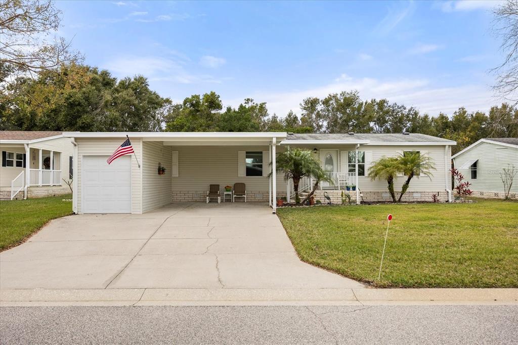 A single-story manufactured home with a carport, concrete driveway, and a front lawn — 2632 LAKE GRASSMERE CIRCLE UNIT 1854, ZELLWOOD, FL