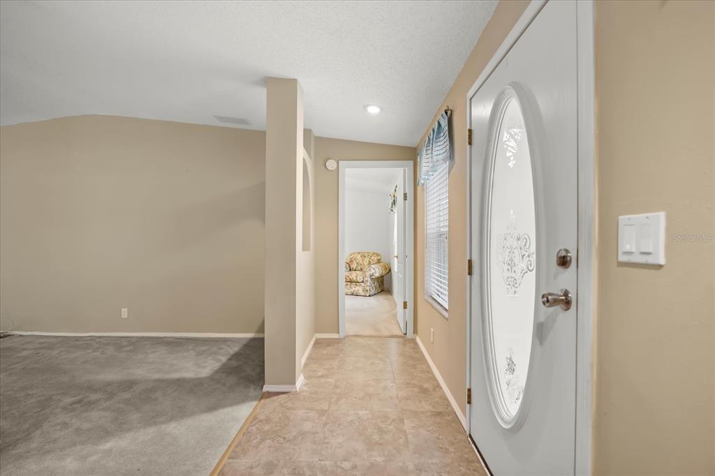 An entryway with tile flooring leads to a carpeted living area and a hallway — 2632 LAKE GRASSMERE CIRCLE UNIT 1854, ZELLWOOD, FL