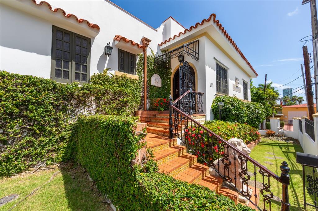 A white Mediterranean-style house features a tiled staircase, wrought iron railings, and lush green ivy — 550 WAYMOUTH, MIRAMAR, SAN JUAN, PR