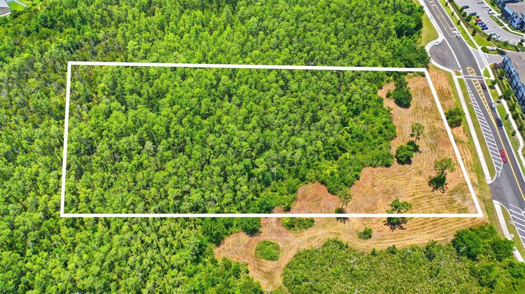 An aerial view shows a rectangular plot of land featuring dense forest and cleared areas — 00 CORPORATE CAMPUS WAY, ST CLOUD, FL