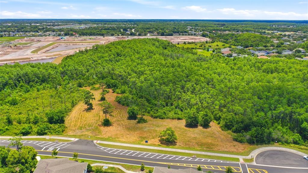 An aerial view shows a vacant, wooded lot bordering a paved road and residential area — 00 CORPORATE CAMPUS WAY, ST CLOUD, FL