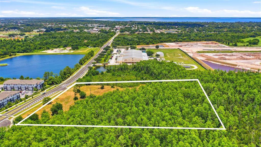 An aerial view shows a rectangular plot of wooded land outlined in white near buildings — 00 CORPORATE CAMPUS WAY, ST CLOUD, FL