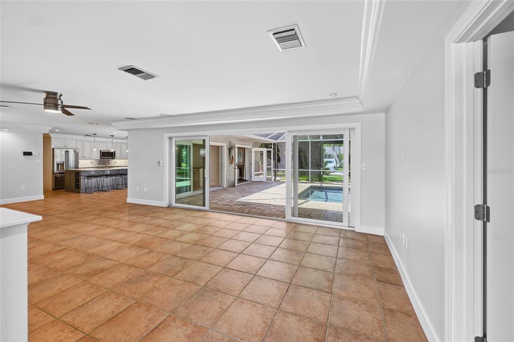 A tiled living room features sliding glass doors opening to a pool patio and kitchen — 606 OWL WAY, SARASOTA, FL