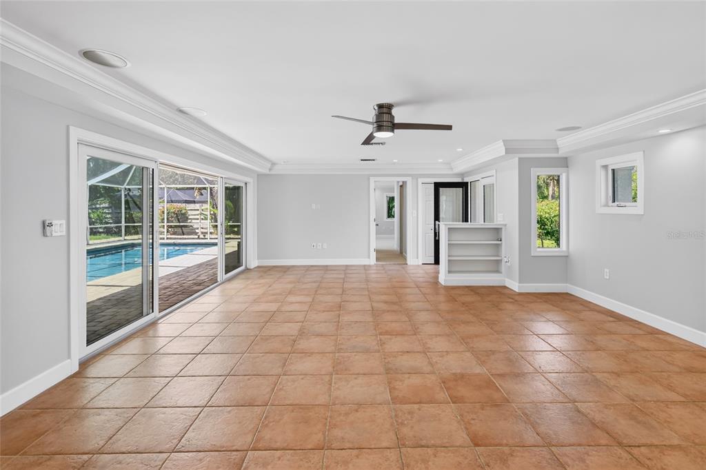 A spacious room with light gray walls, tile flooring, a ceiling fan, and sliding glass doors — 606 OWL WAY, SARASOTA, FL