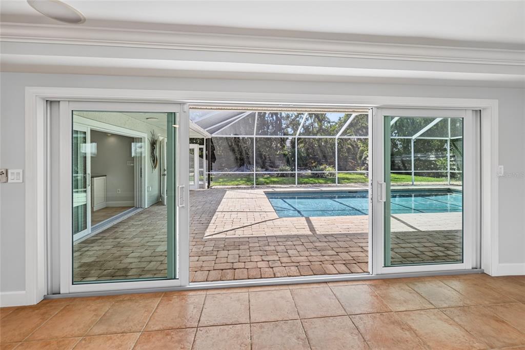 A room with tile flooring looks out through large sliding glass doors to a pool — 606 OWL WAY, SARASOTA, FL