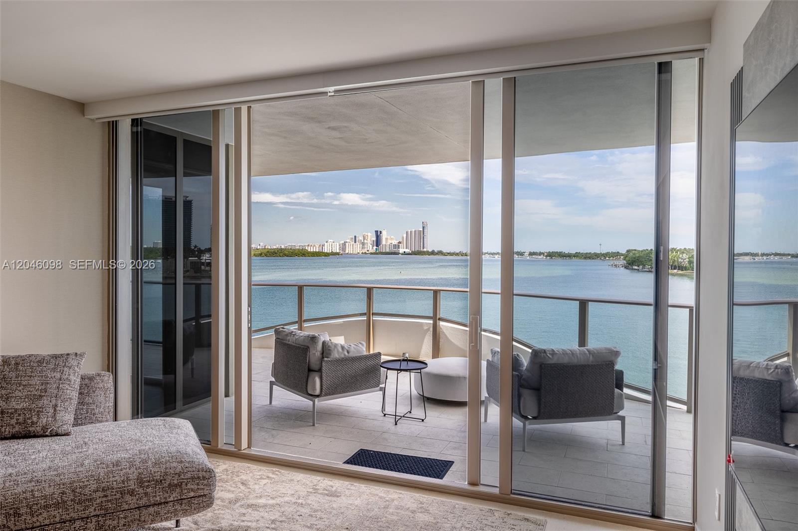 A living room opens through sliding glass doors to a balcony overlooking a bay — 1135 103rd St # 405, Bay Harbor Islands FL 33154, BAY HARBOR ISLANDS, FL