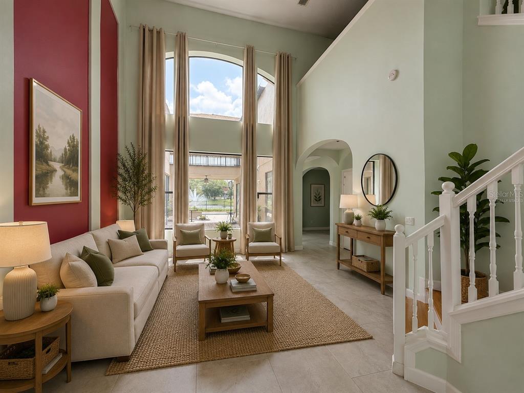 A living room with high ceilings, large windows, a red accent wall, and a staircase — 10068 SILVER LAUREL WAY, ORLANDO, FL